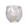 Clear glass tealight holder with snowflake cutout pattern and lit white candle inside.