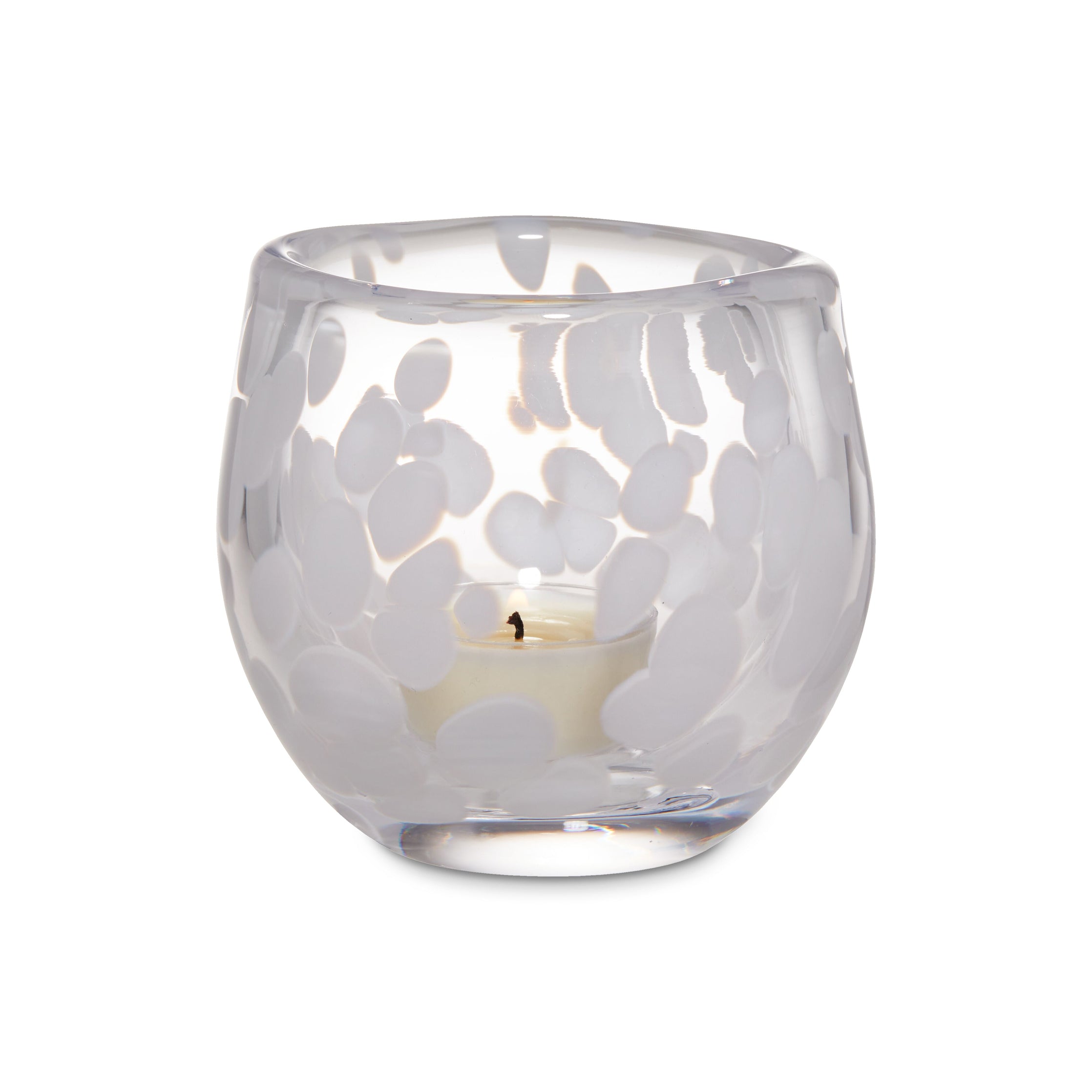 Clear glass tealight holder with snowflake cutout pattern and lit white candle inside.