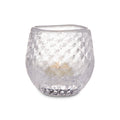 Clear glass tealight holder with textured bubble pattern containing a lit cream-colored candle.