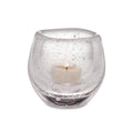Clear glass tealight holder with cream-colored tealight candle inside.