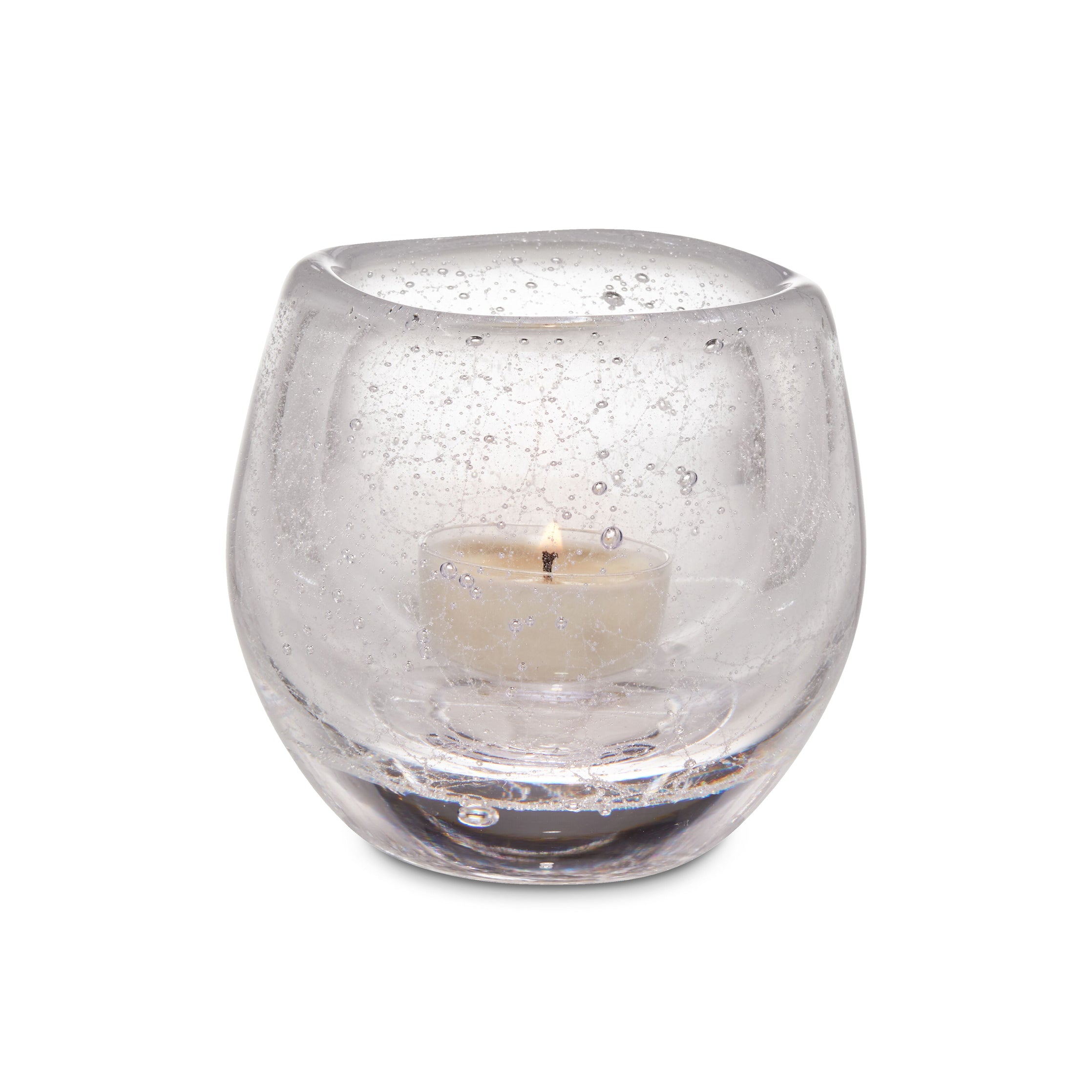 Clear glass tealight holder with cream-colored tealight candle inside.