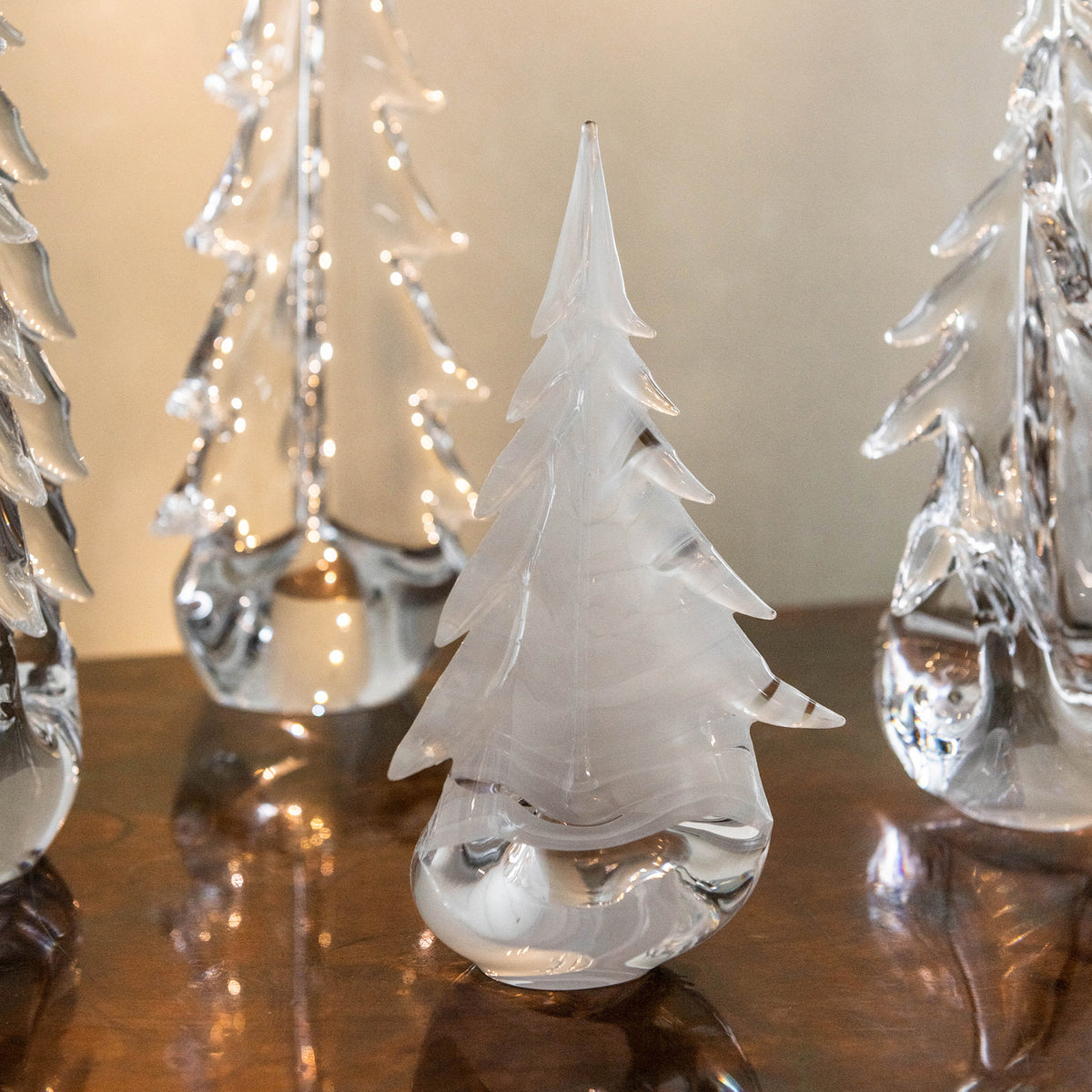 Frosted glass evergreen tree with pointed top and textured snow details, surrounded by similar decorative trees with small li