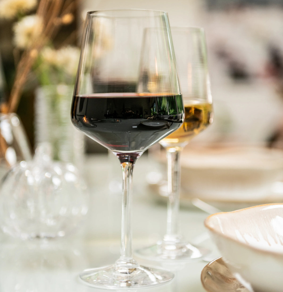 Two wine glasses on a table, one filled with red wine and one with white wine.