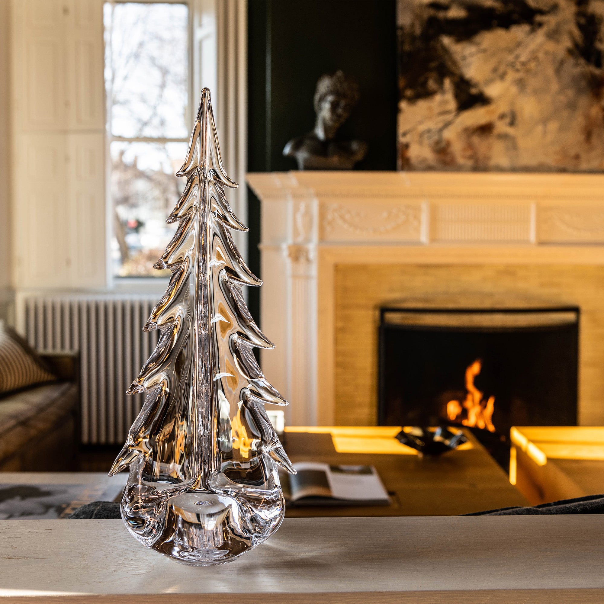 Clear glass evergreen tree sculpture with layered branches displayed on a wooden table.