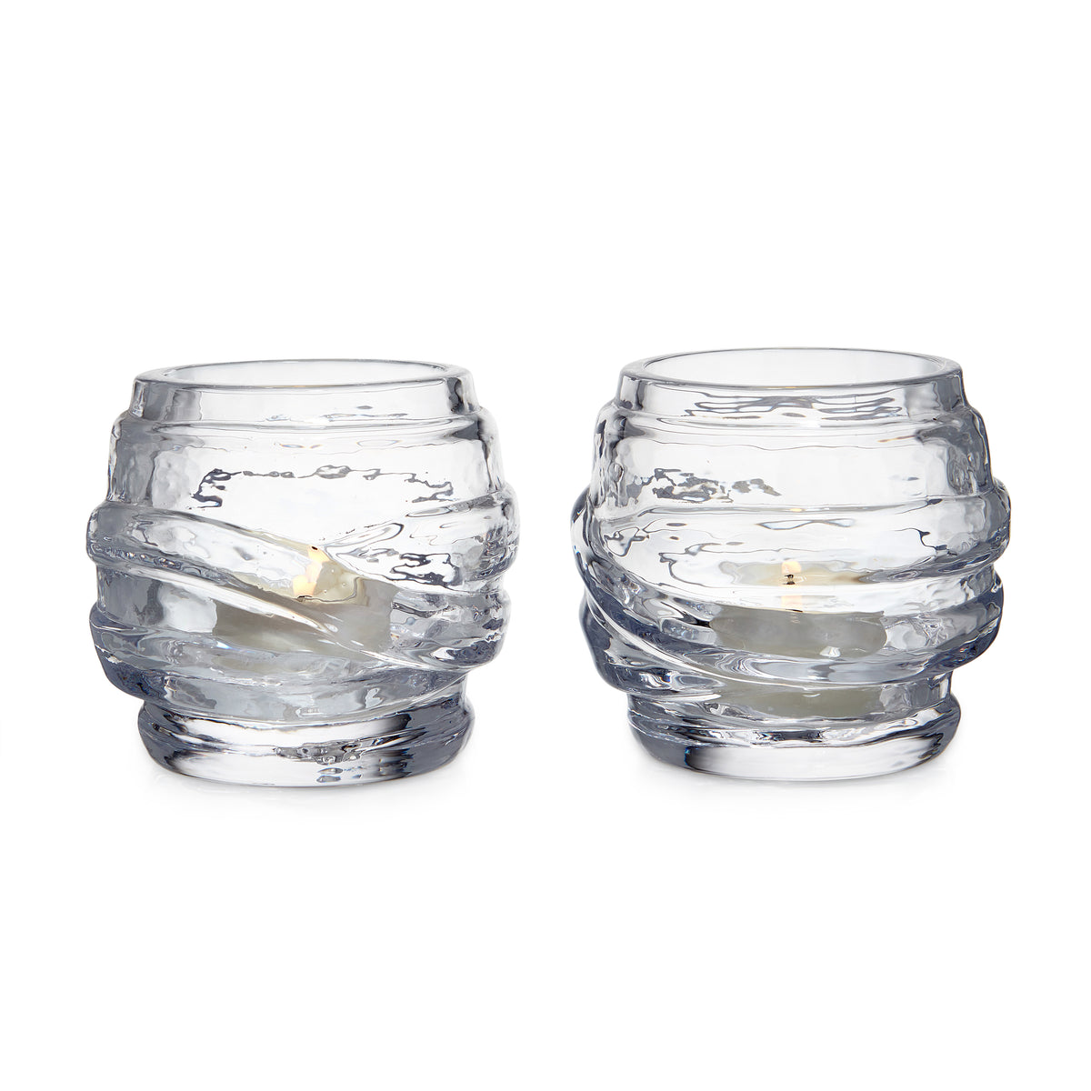 Two clear glass tealight holders with textured wrap design, each containing a small cream-colored candle.