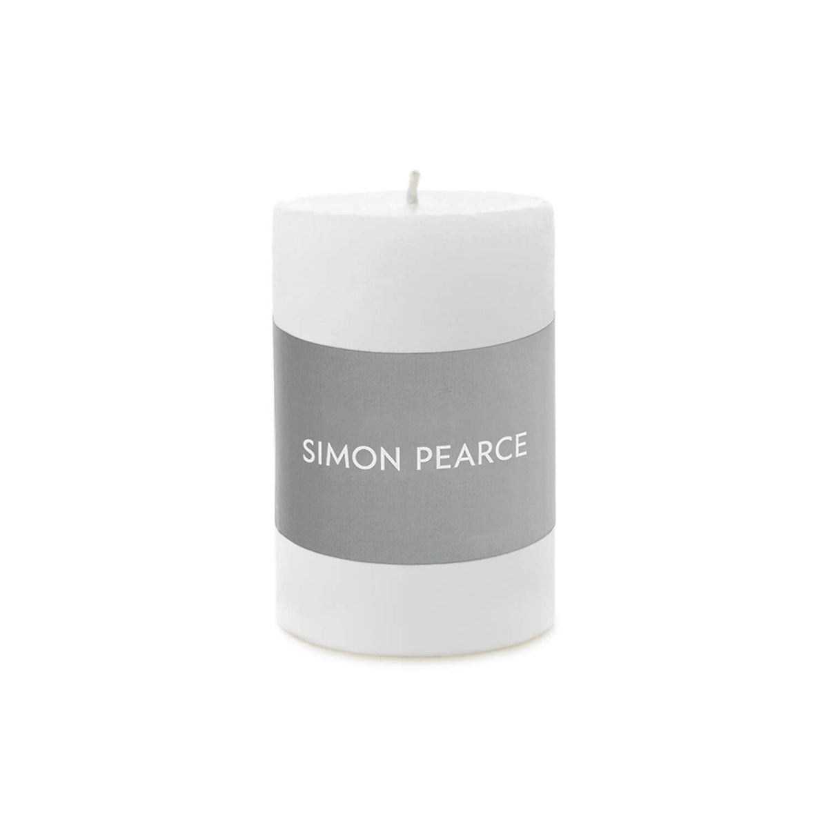 White cylindrical pillar candle with gray band labeled "SIMON PEARCE" and visible wick on top.