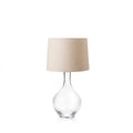 Clear glass teardrop-shaped base with cream linen drum shade and metal stem.